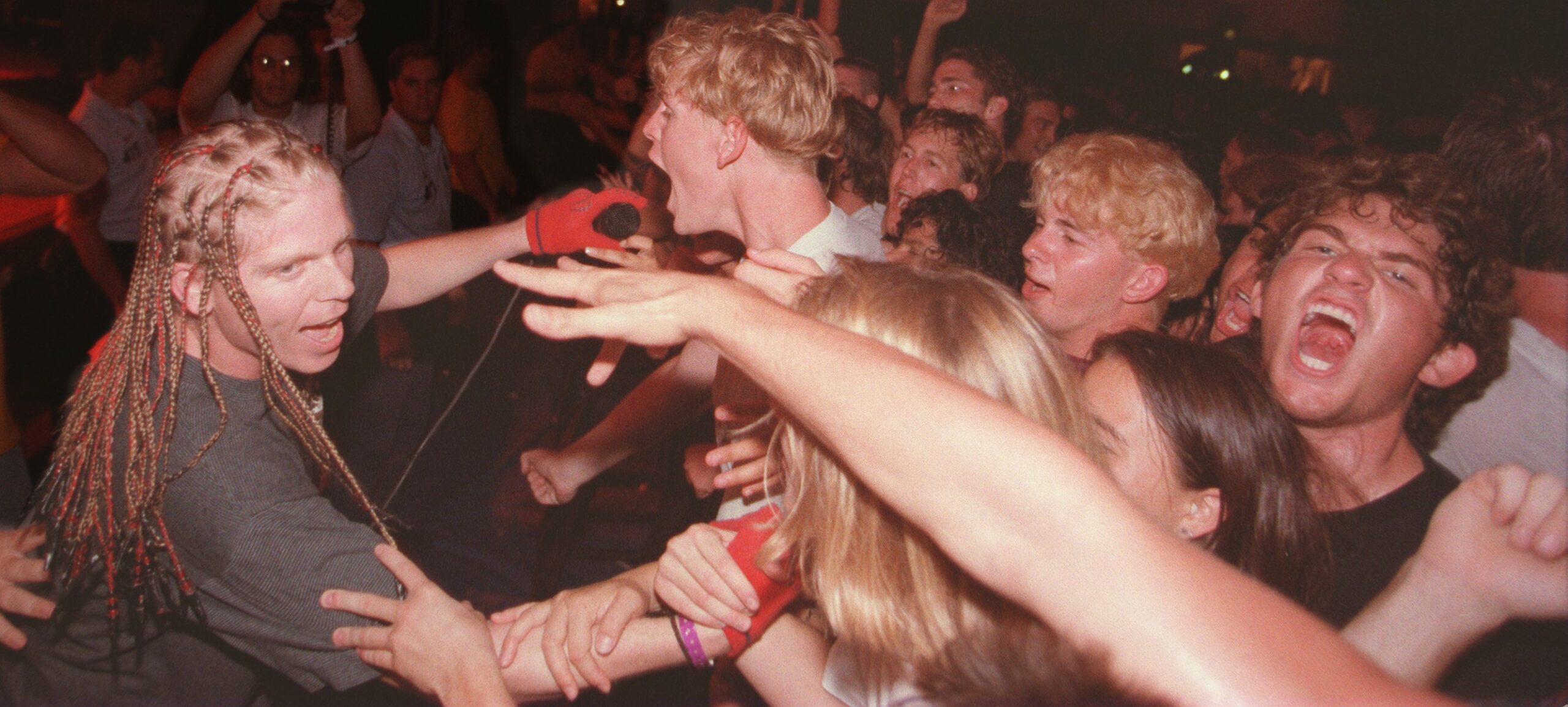 The-Offspring.Sänger Dexter Holland hält live einem Fan in der ersten Reihe ein Mikrofon hin, in das dieser hineinschreit.